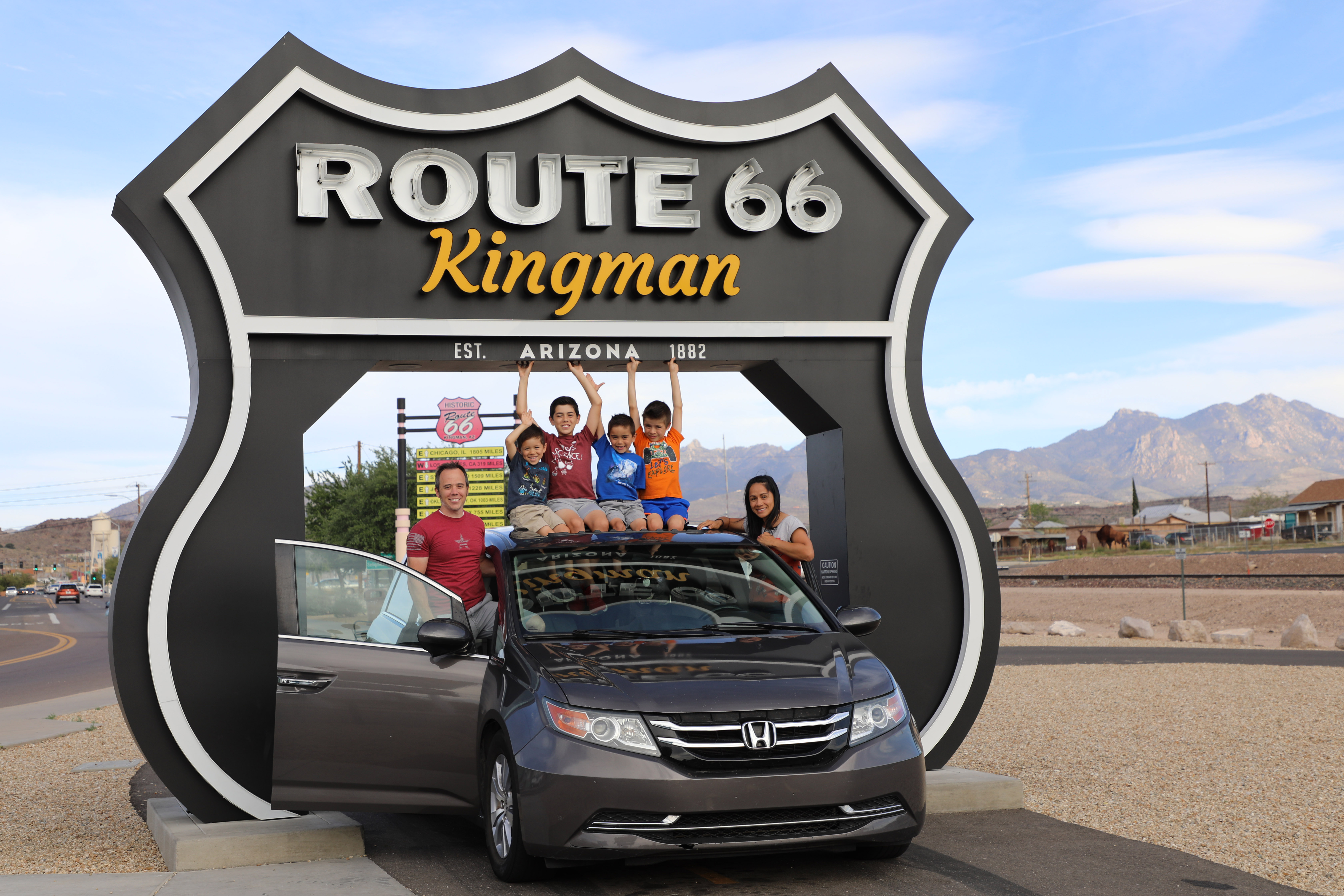 A family posing at the Route 66 Drive-Thru Shield in Kingman, Arizona