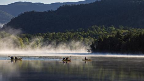 在纽约州阿迪朗达克山脉的镜湖上划皮划艇