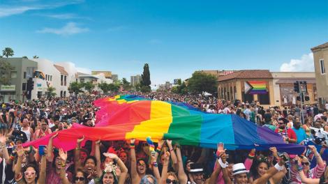 Participants kicking off the San Diego Pride parade with a large rainbow flag Participants kicking off the San Diego Pride parade with a large rainbow flag