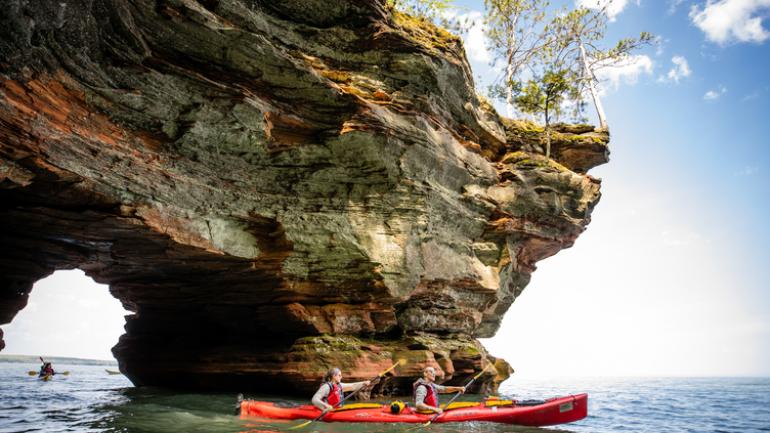 乘皮划艇穿过威斯康星州阿波斯特尔群岛国家湖滨区的海蚀洞 乘皮划艇穿过威斯康星州阿波斯特尔群岛国家湖滨区的海蚀洞