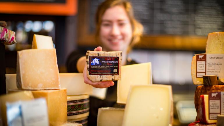 在威斯康星州麦迪逊的 Fromagination 区一位女士拿着奶酪块 在威斯康星州麦迪逊的 Fromagination 区一位女士拿着奶酪块