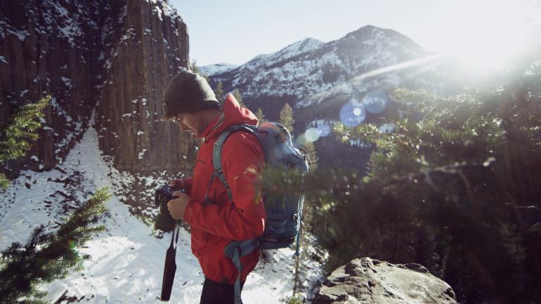 Max Lowe checking camera settings while hiking in Montana