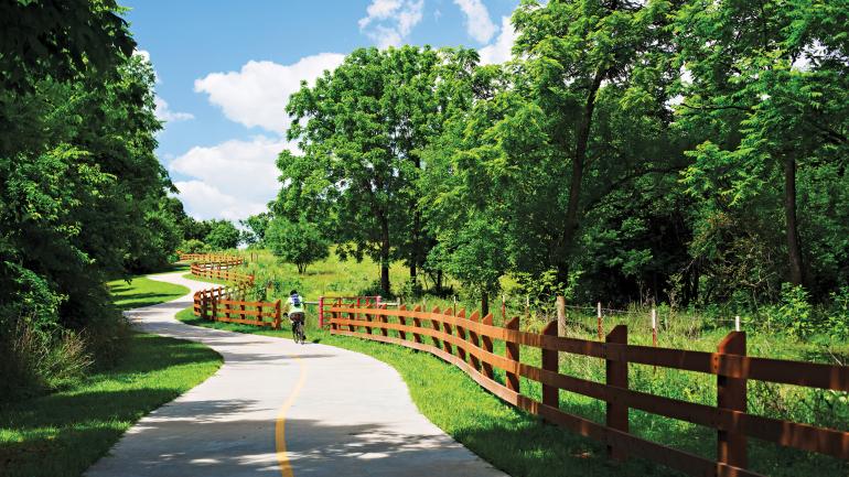 一位公路自行车手蜿蜒盘旋在 Razorback Regional Greenway 绿道上