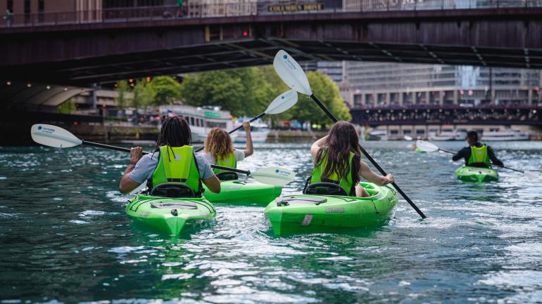 在芝加哥河上划着皮划艇穿越城市中心