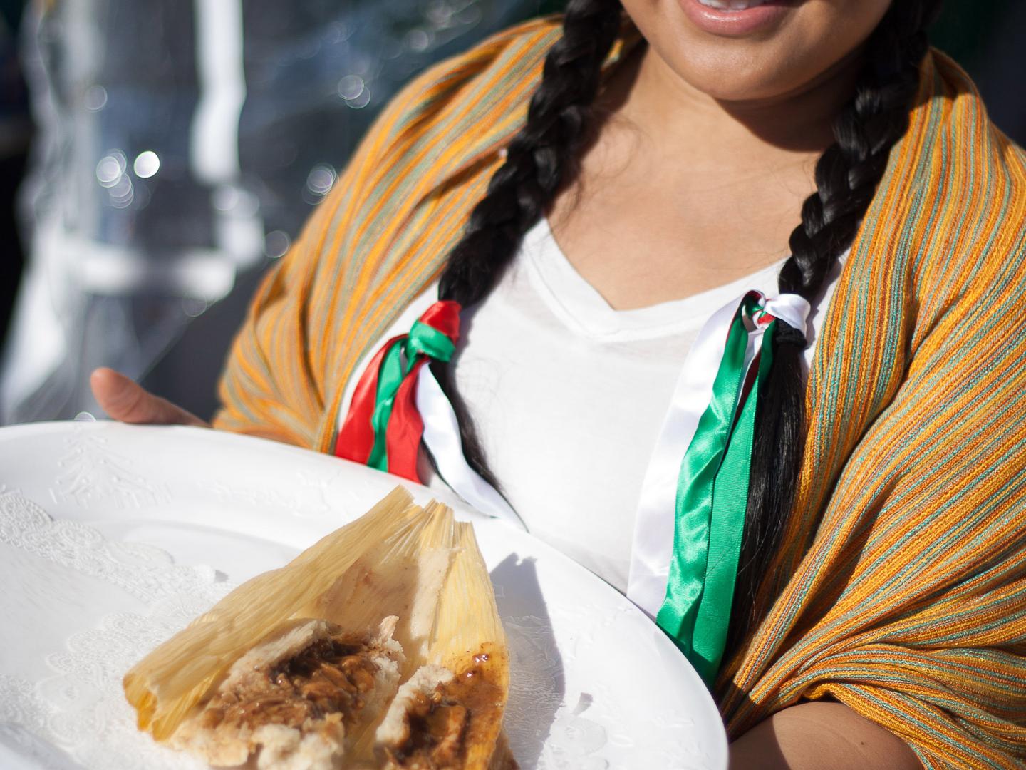 印第奥国际玉米粉蒸肉节上端着一盘玉米粉蒸肉的女士