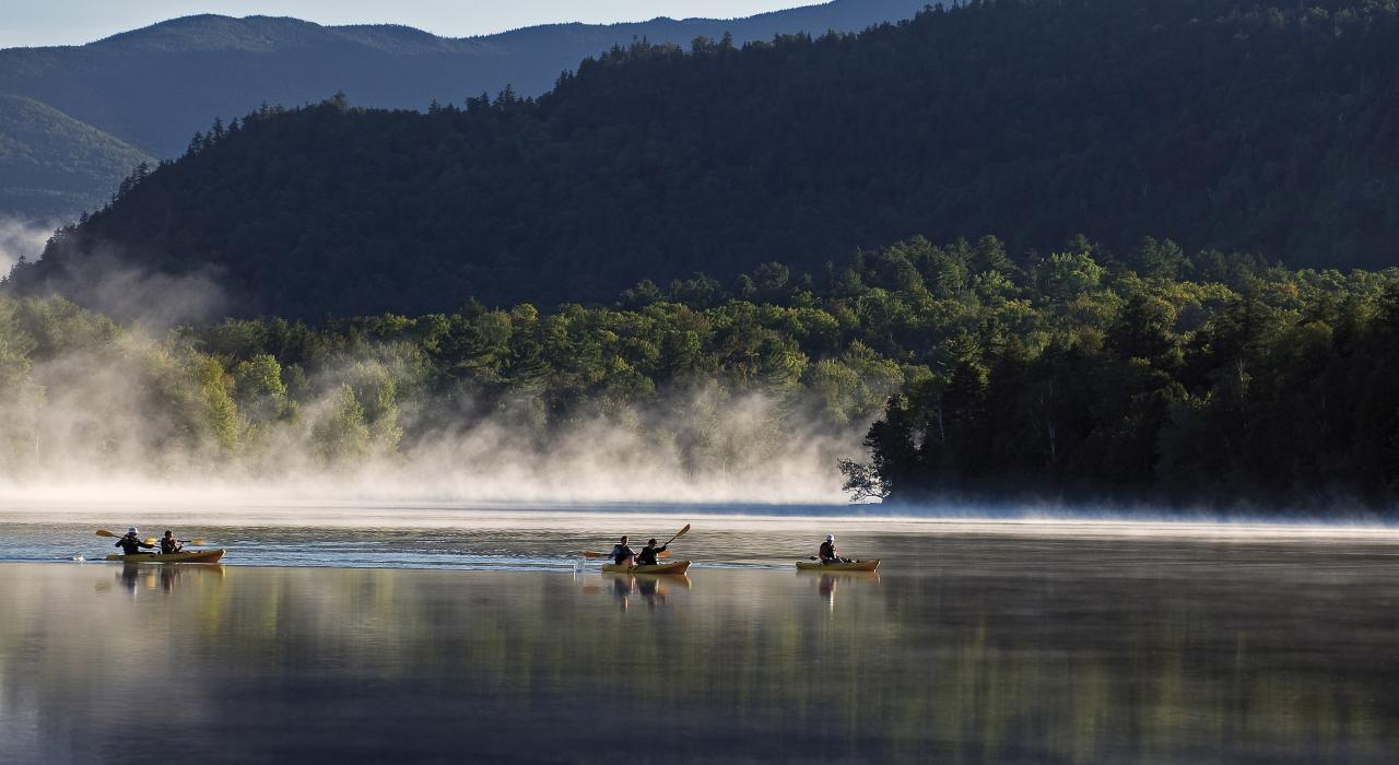 在纽约州阿迪朗达克山脉的镜湖上划皮划艇