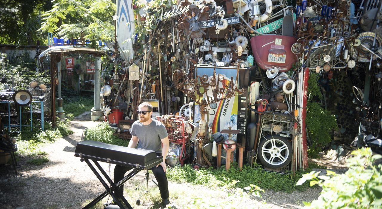音乐家 Dr.Joe 在德克萨斯州奥斯汀的后院艺术项目“垃圾教堂”旁弹琴