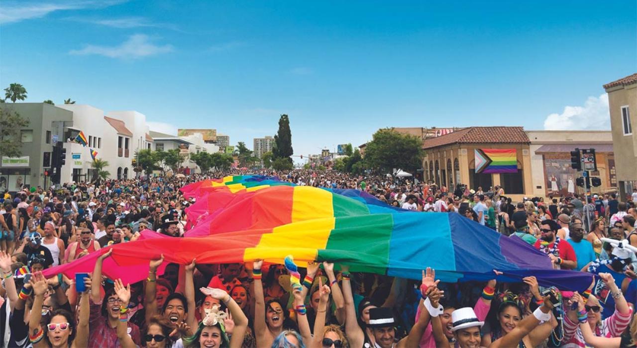 参与者们高举大型彩虹旗，激动地庆祝圣地亚哥骄傲节游行活动