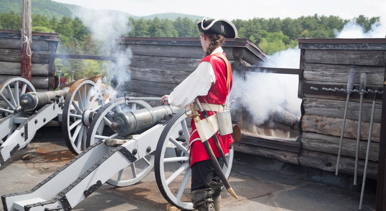 一位身着传统服饰的导游展示威廉亨利堡 (Fort William Henry) 的一只大炮