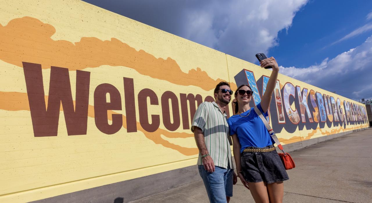 在维克斯堡市中心的“Welcome to Vicksburg”的墙绘前留影